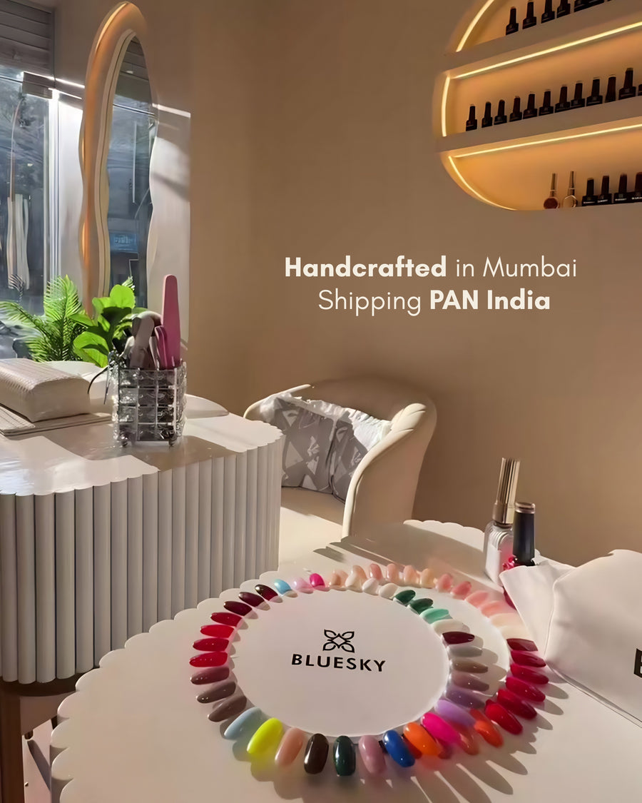 Adore Nails salon interior with illuminated oval nail polish display shelf, cream chairs, and a client's manicured hands resting on a white table — nail studio in Kandivali West, Mumbai